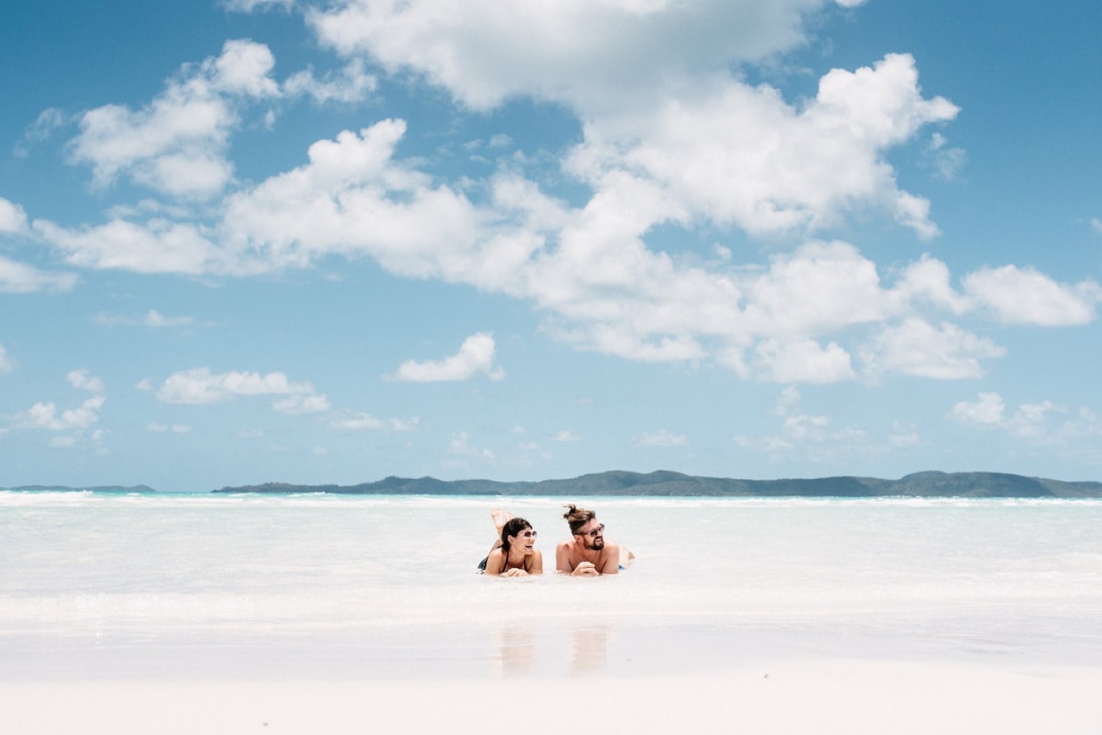 Couple relaxing in shallow water at Whitehaven Beach, Whitsunday Islands, Australia