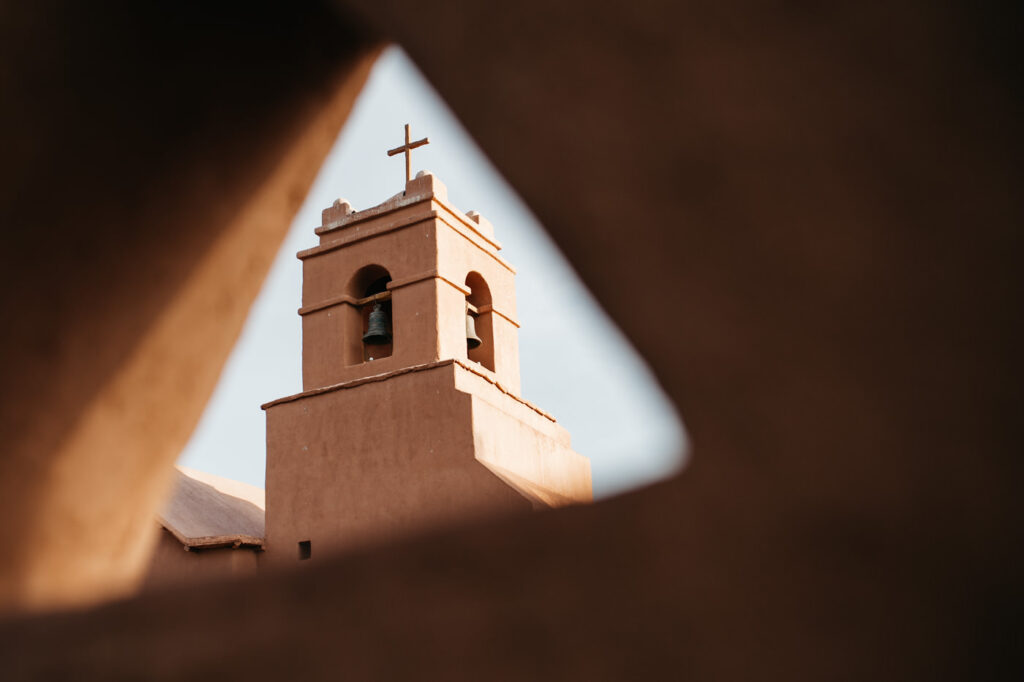 Kirchturm von San Pedro de Atacama durch eine Maueröffnung gesehen