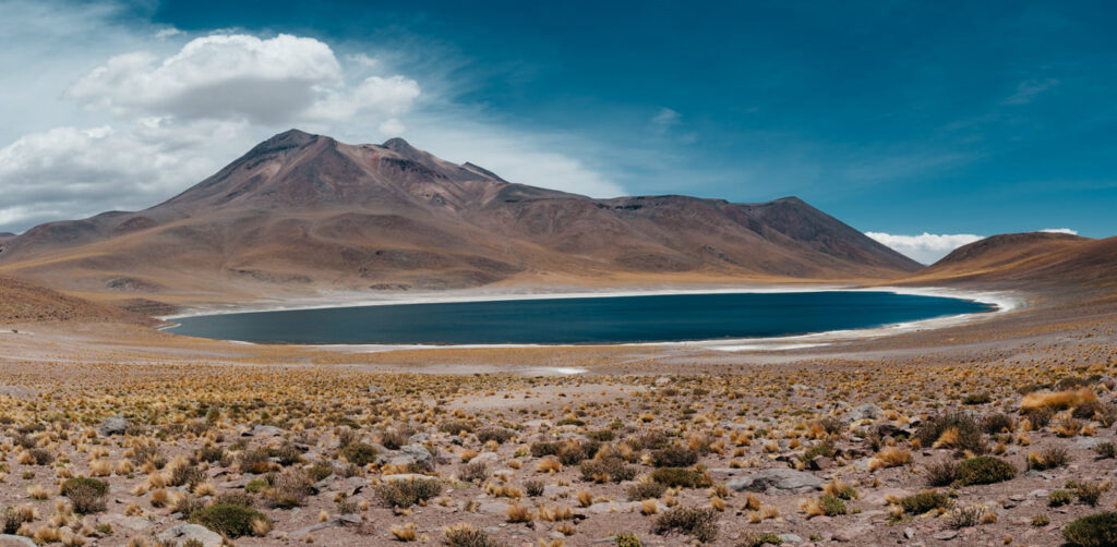 Dunkelblaue Altiplano-Lagune vor kargen Vulkanbergen