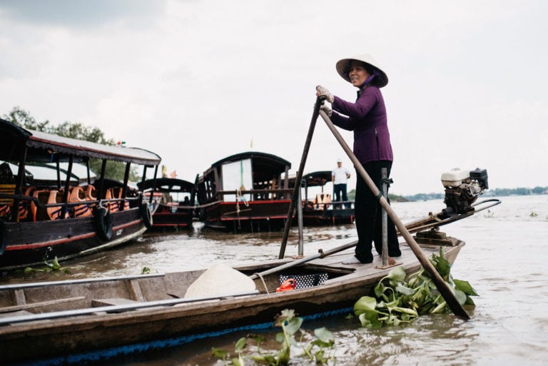 Woman paddling on a small boat in the Mekong Delta