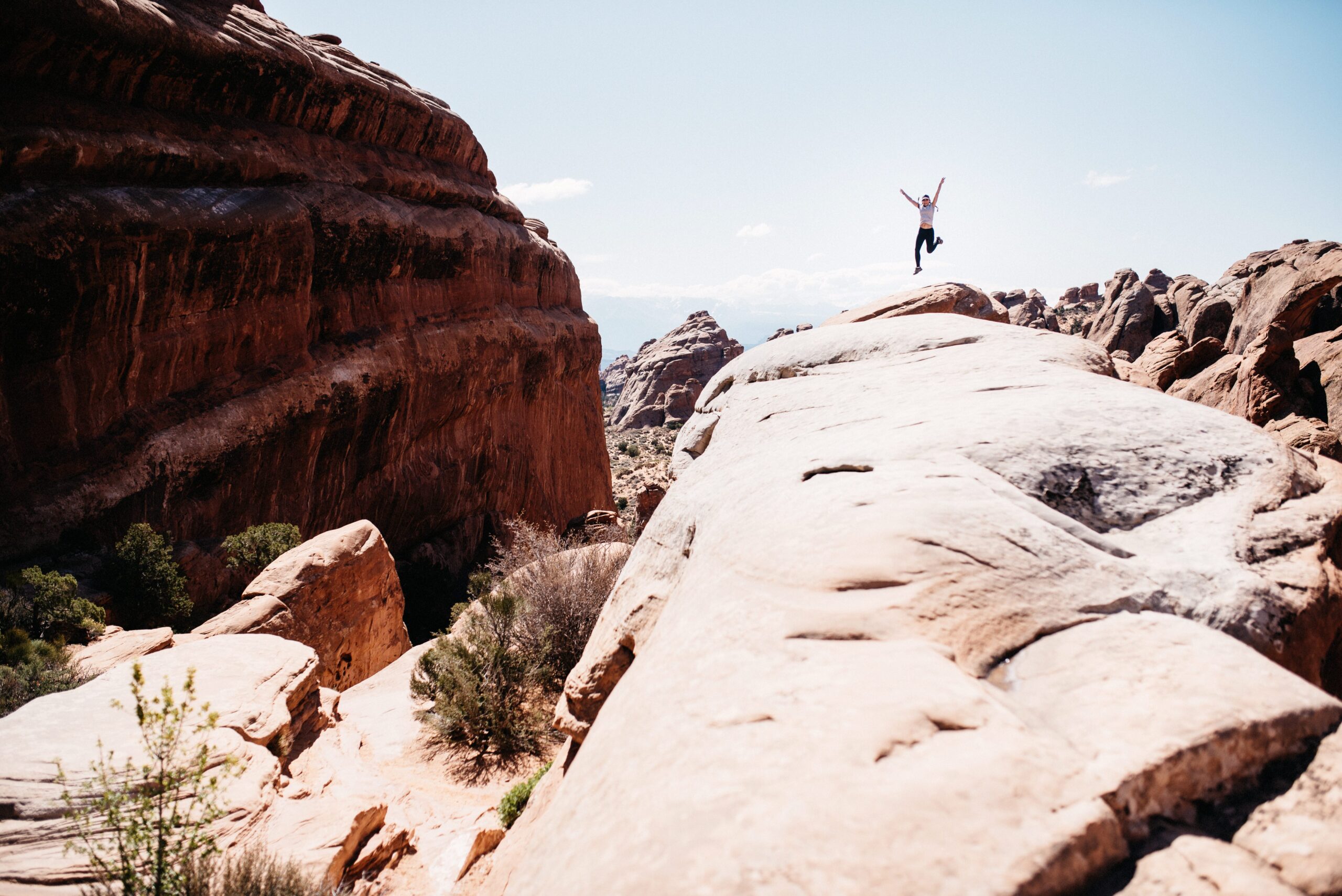 A hiker crossing a narrow sandstone ridge on the Primitive Trail