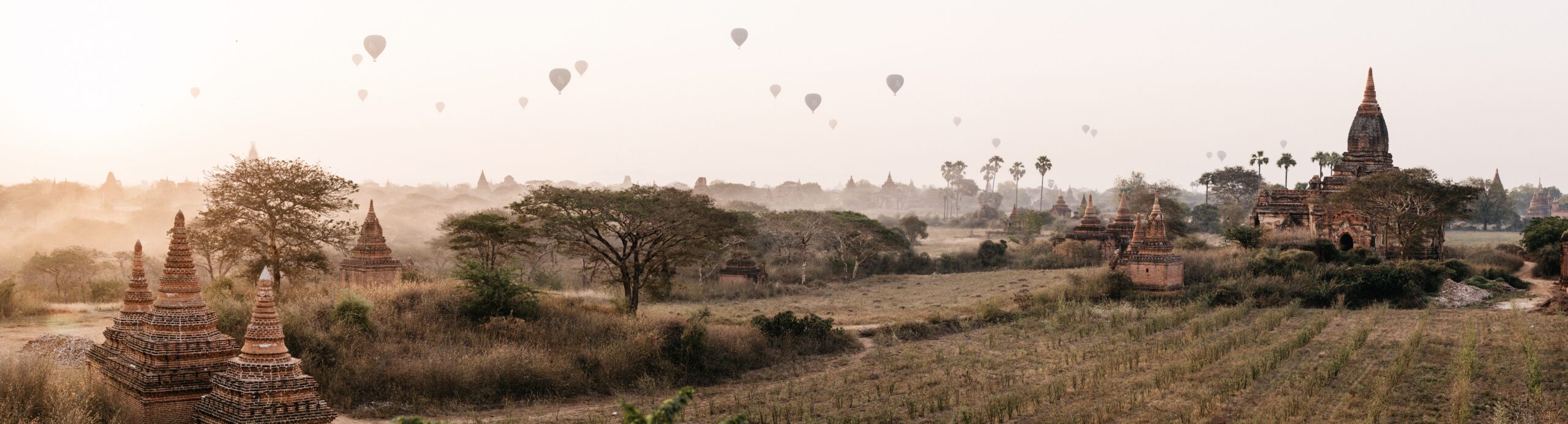 Panoramic sunrise view of temples and hot-air balloons across Bagan