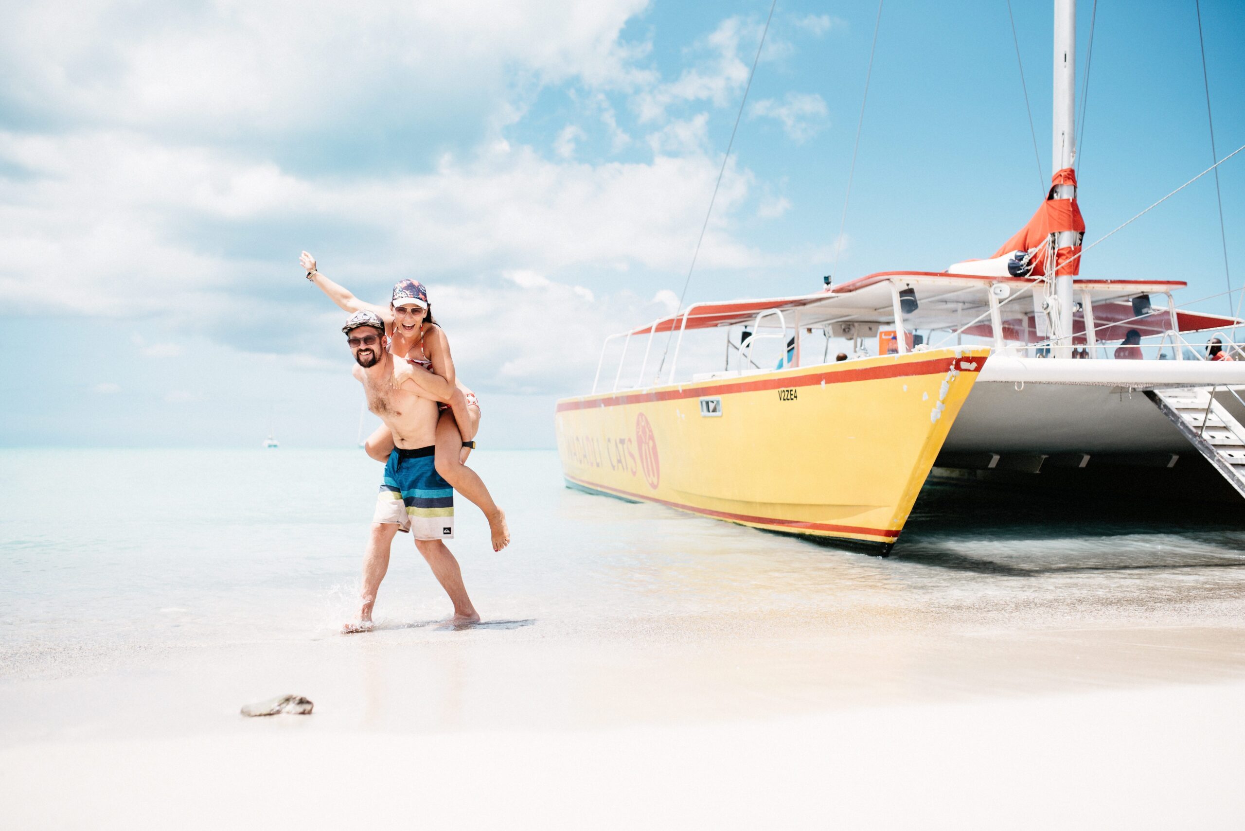 Bianca jumping beside a catamaran on a white beach in Antigua