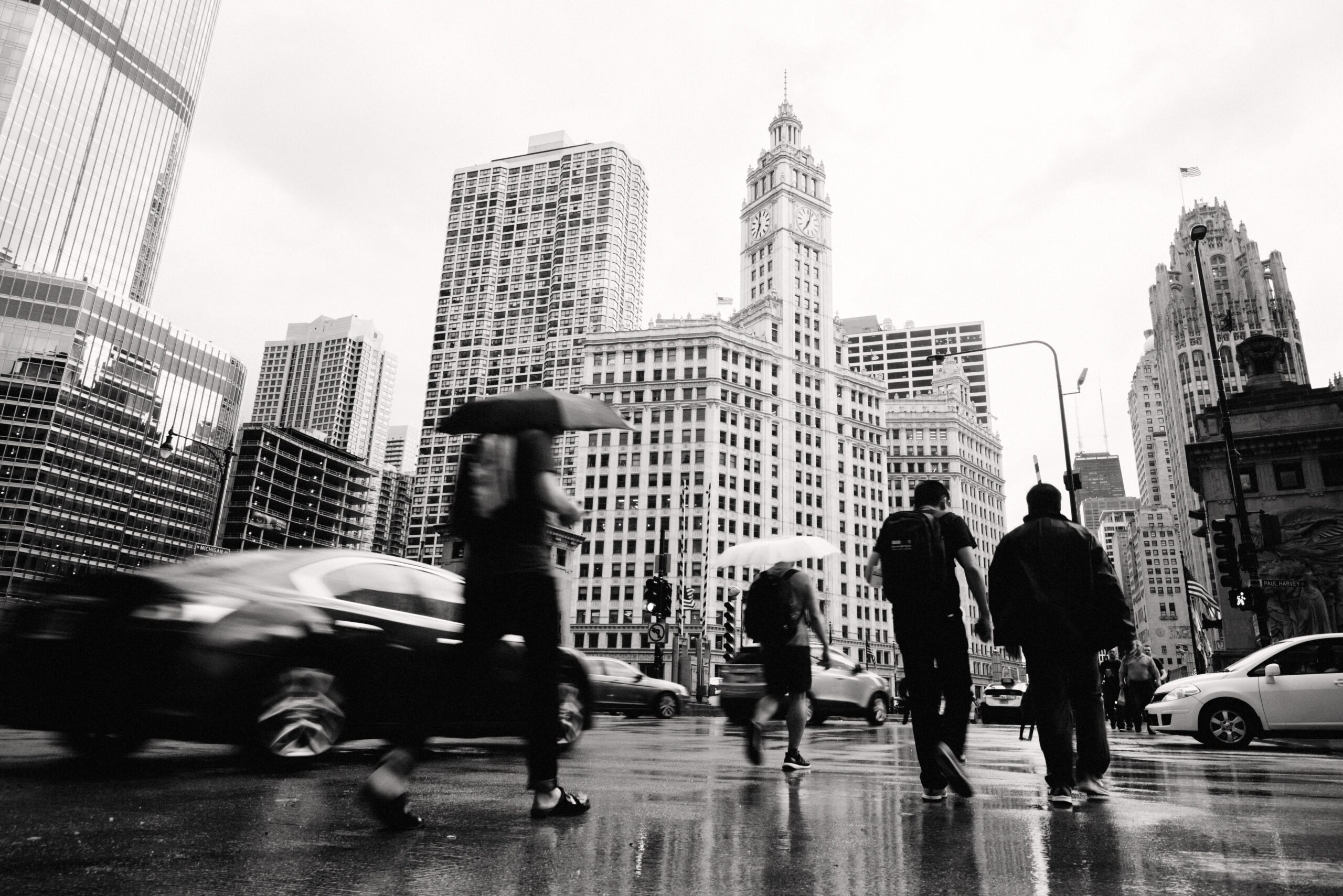 People crossing a rainy street between Chicago skyscrapers