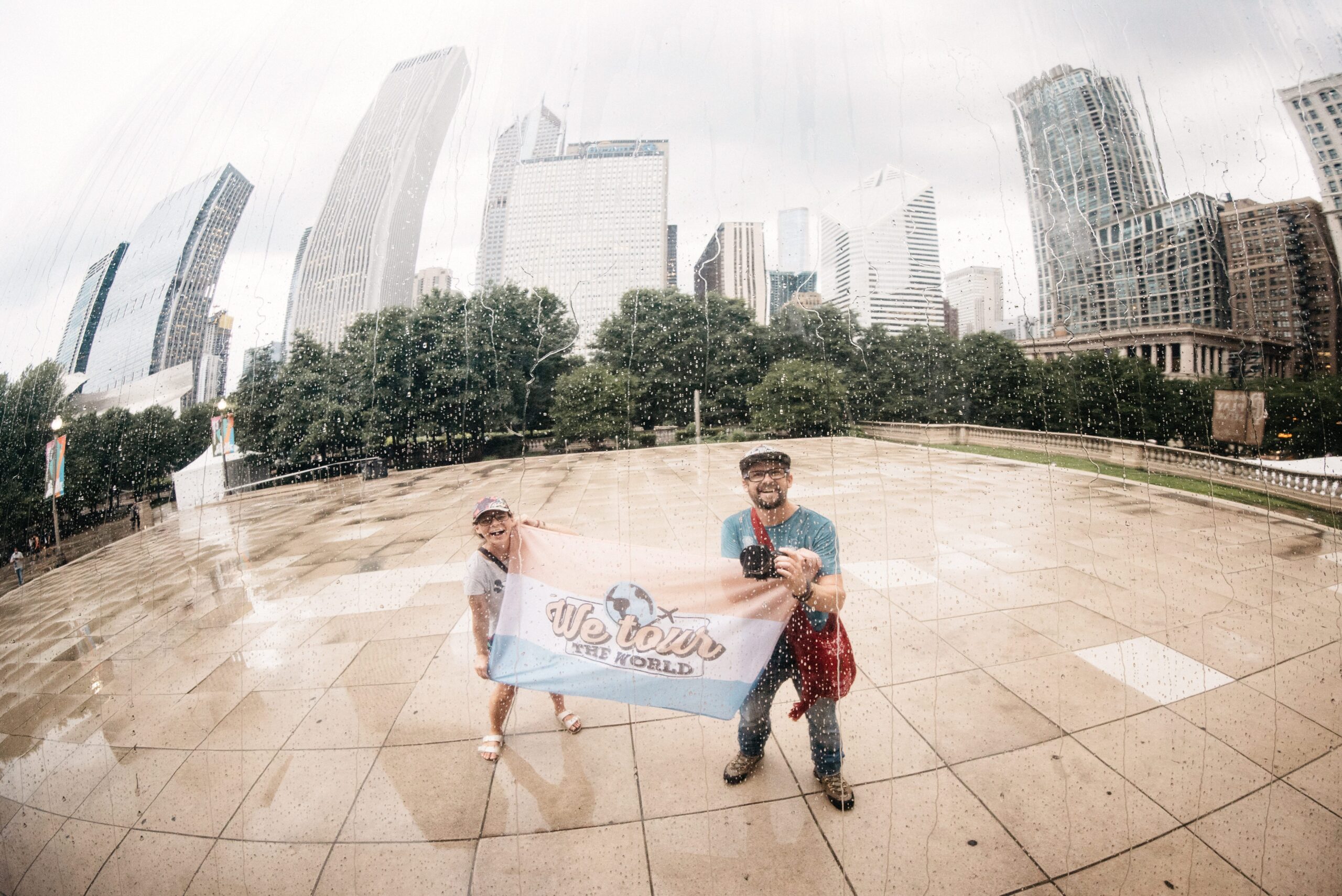 Bianca and Tom with their travel flag at the Cloud Gate sculpture in Chicago