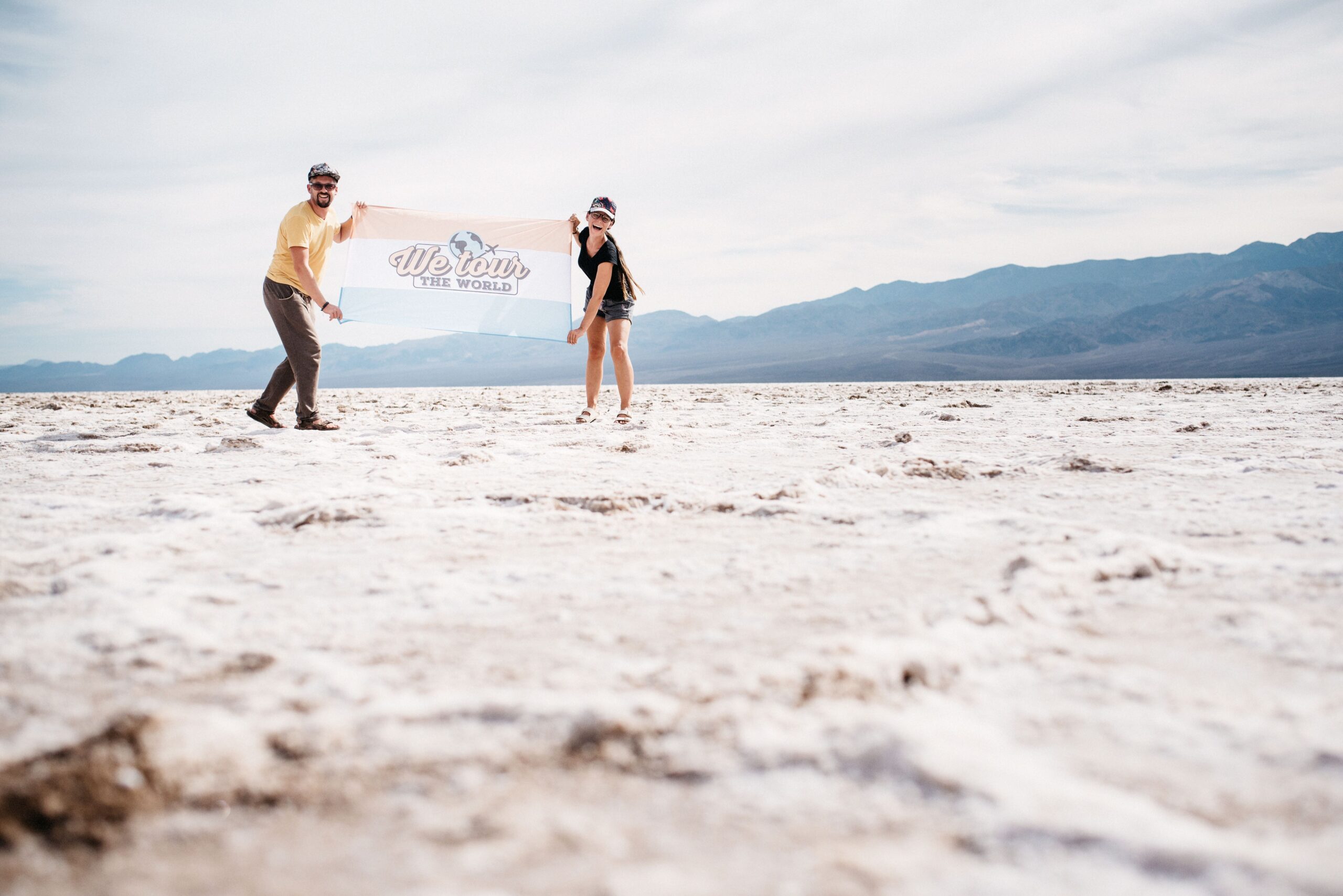 Bianca und Tom halten ihre Reiseflagge im Badwater Basin