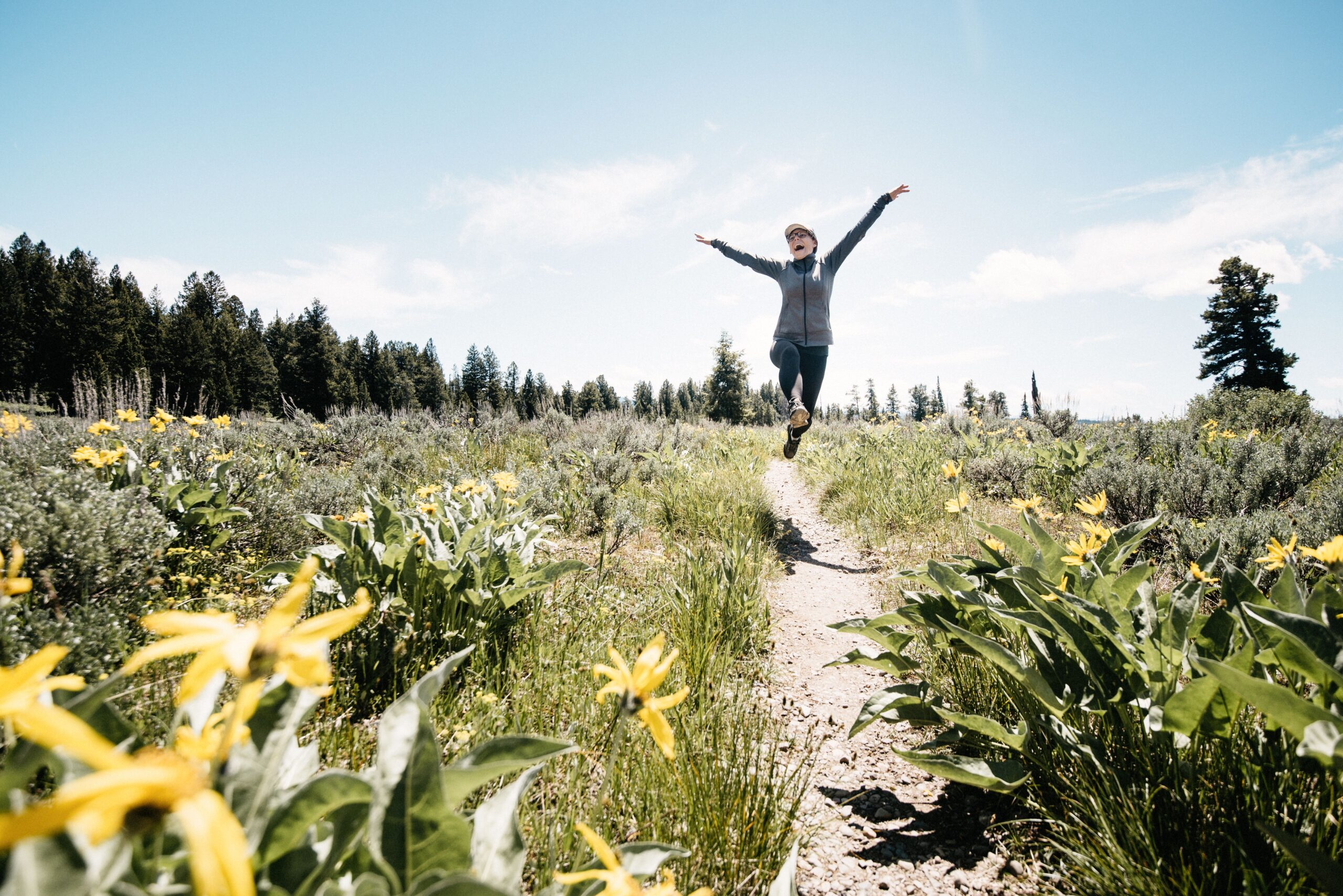 Bianca jumping on a flower-lined trail beside Jackson Lake