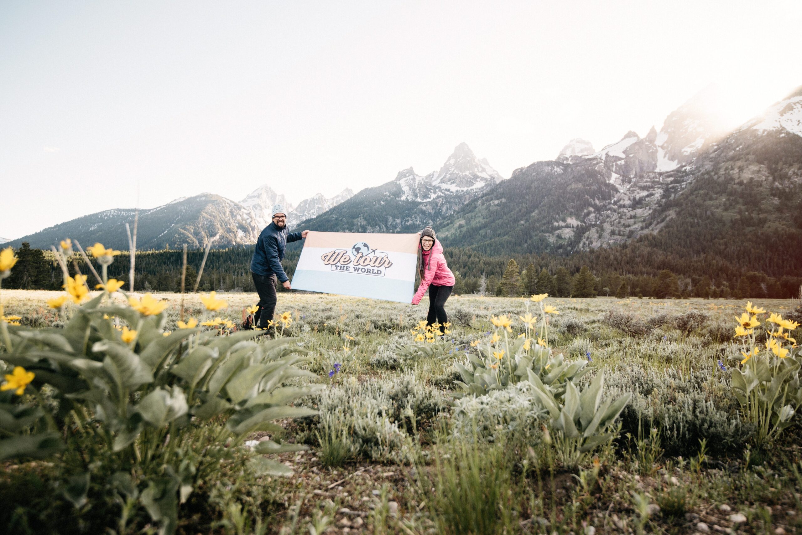 Bianca and Tom holding their travel flag below the Teton Range