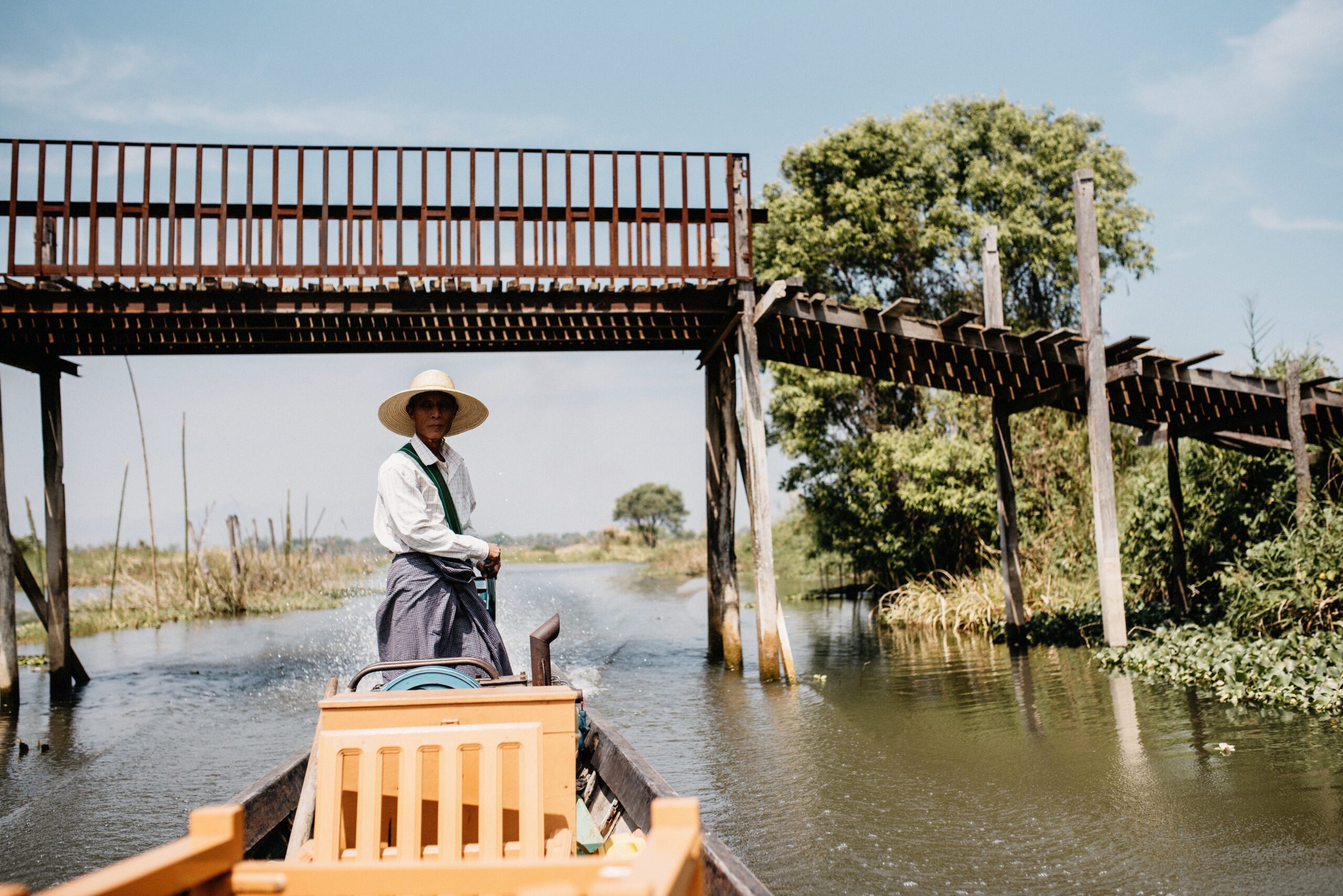 A local boatman navigating beneath a wooden footbridge