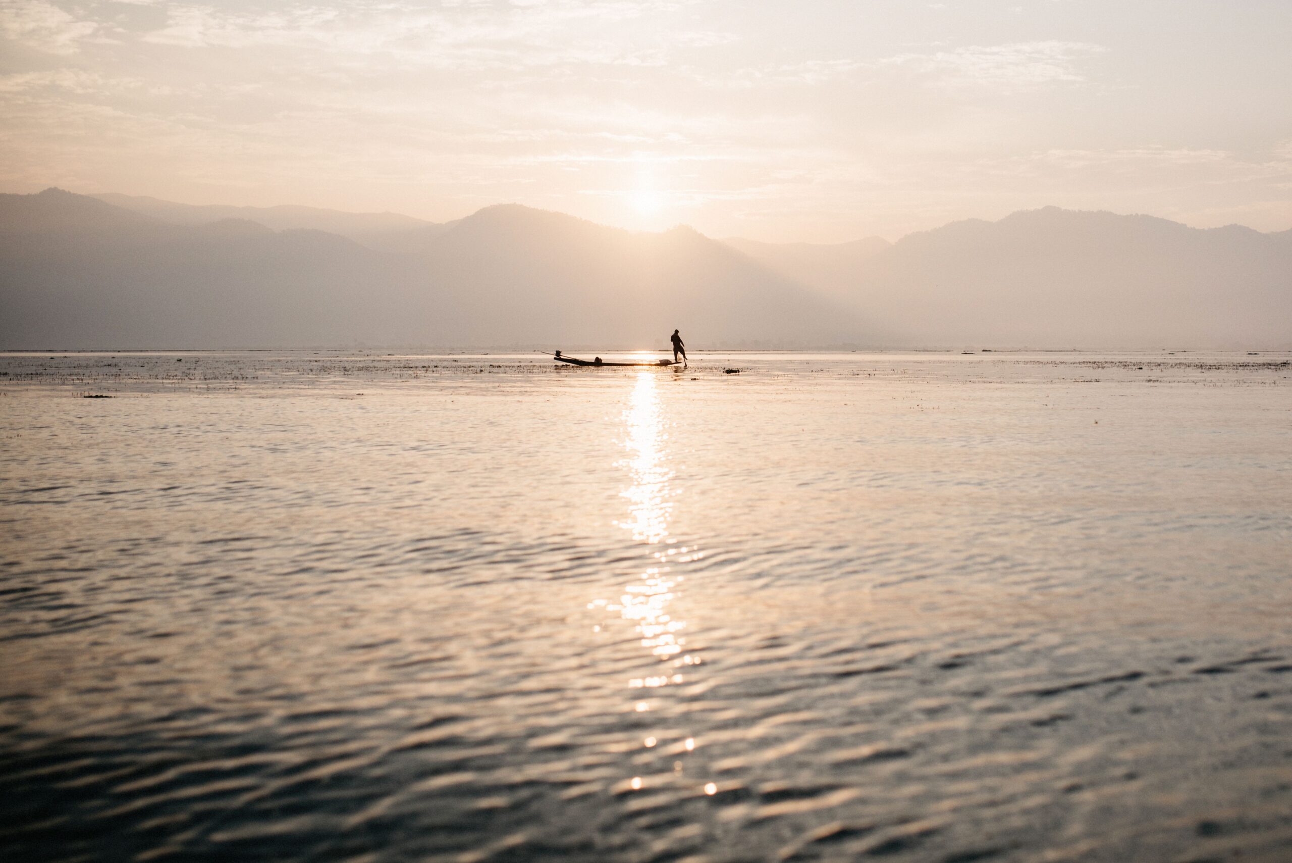 The sun rising behind a long boat on Inle Lake