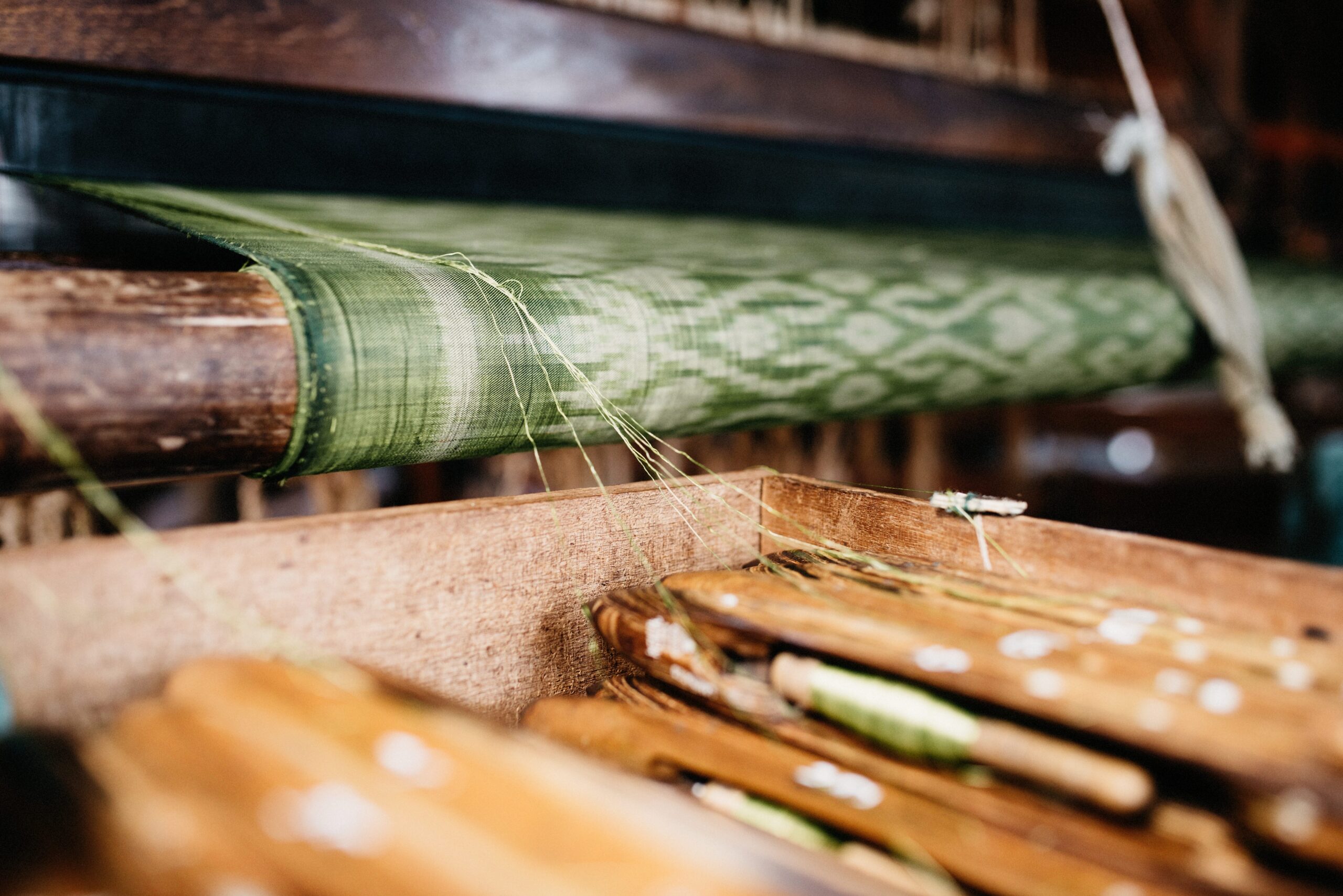 Green lotus fabric taking shape on a traditional loom