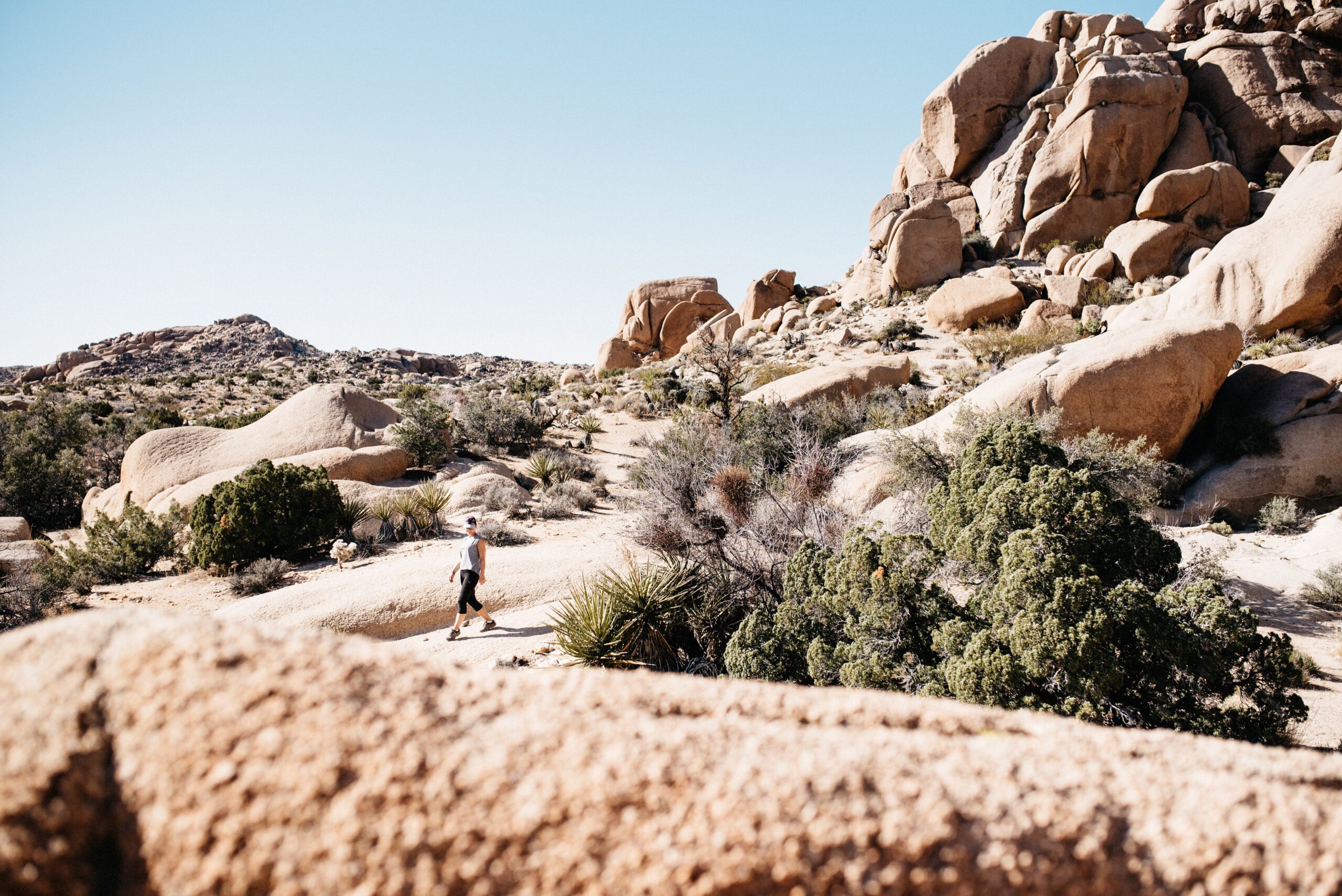 Bianca geht im Joshua Tree Nationalpark zwischen riesigen abgerundeten Felsen hindurch