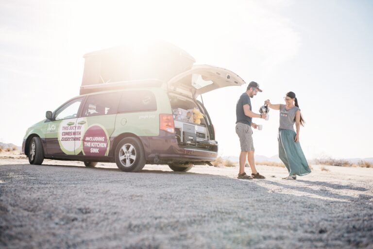 Bianca and Tom beside their campervan in the desert at Joshua Tree National Park