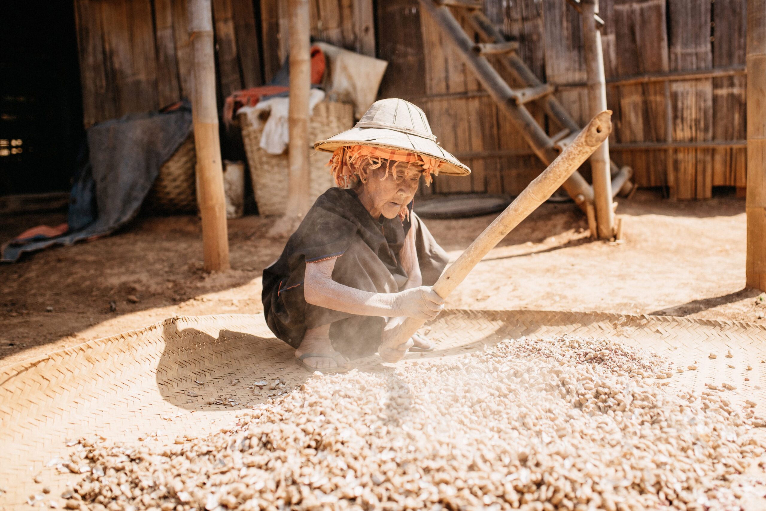 A woman separating peanuts from their shells in a village home