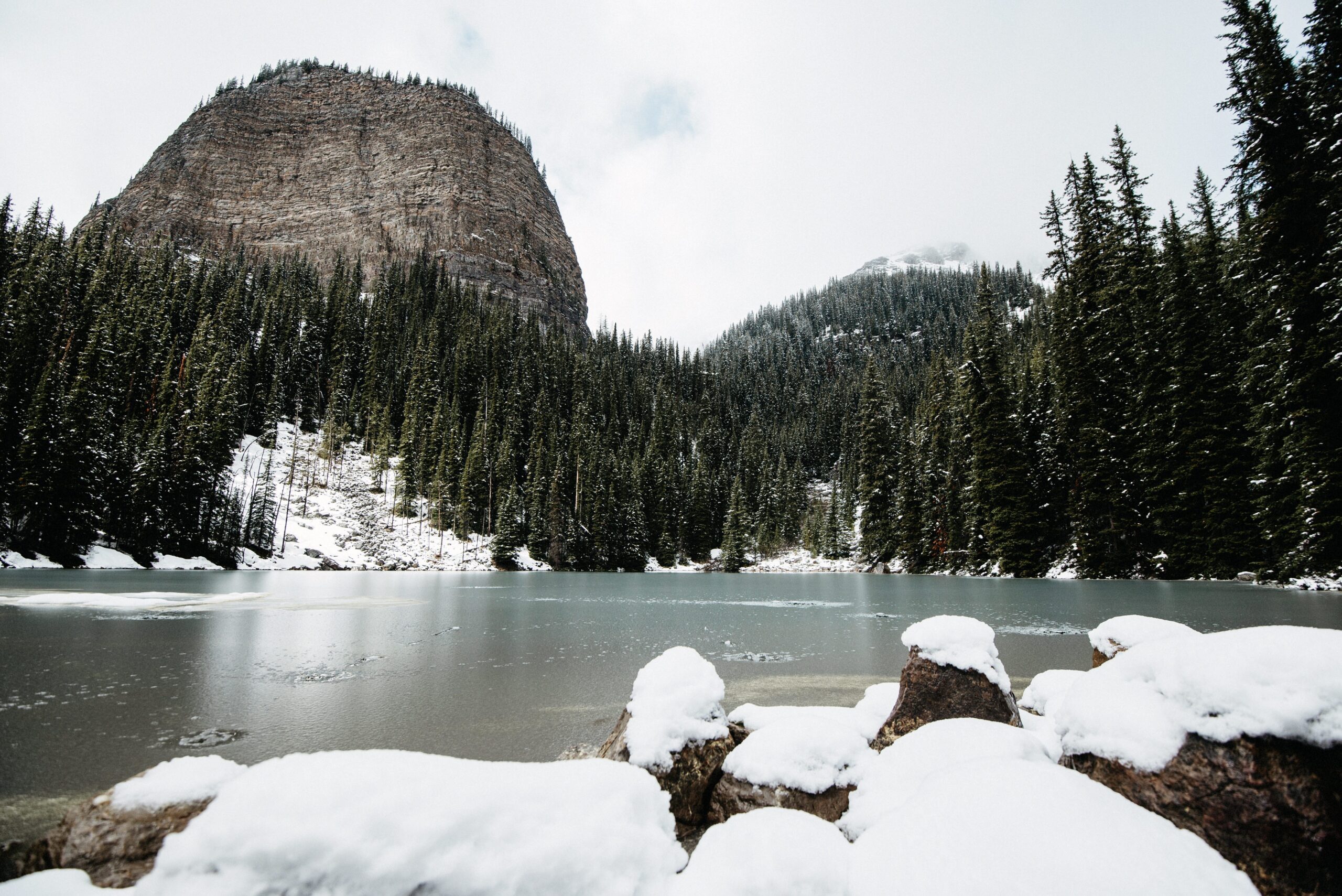 A small frozen mountain lake surrounded by forest