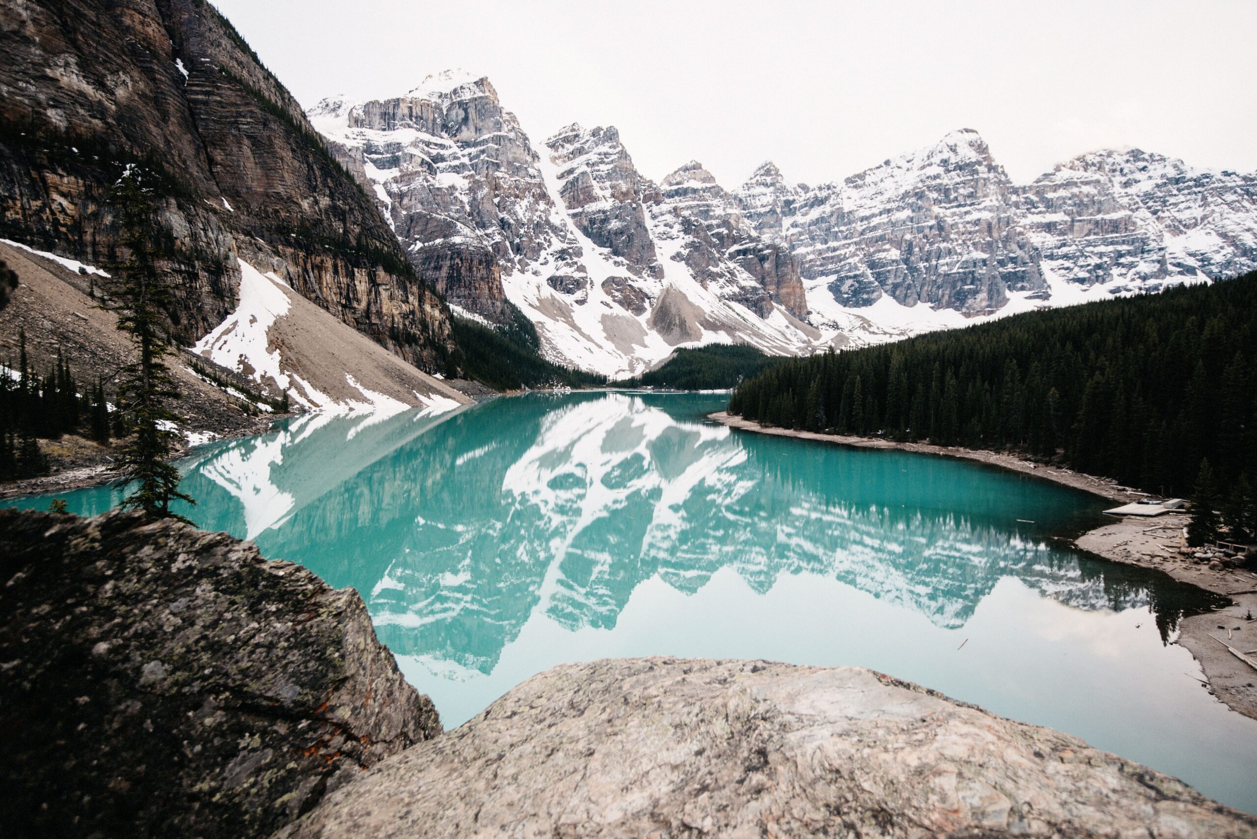 Bianca walking through snow above a turquoise mountain lake