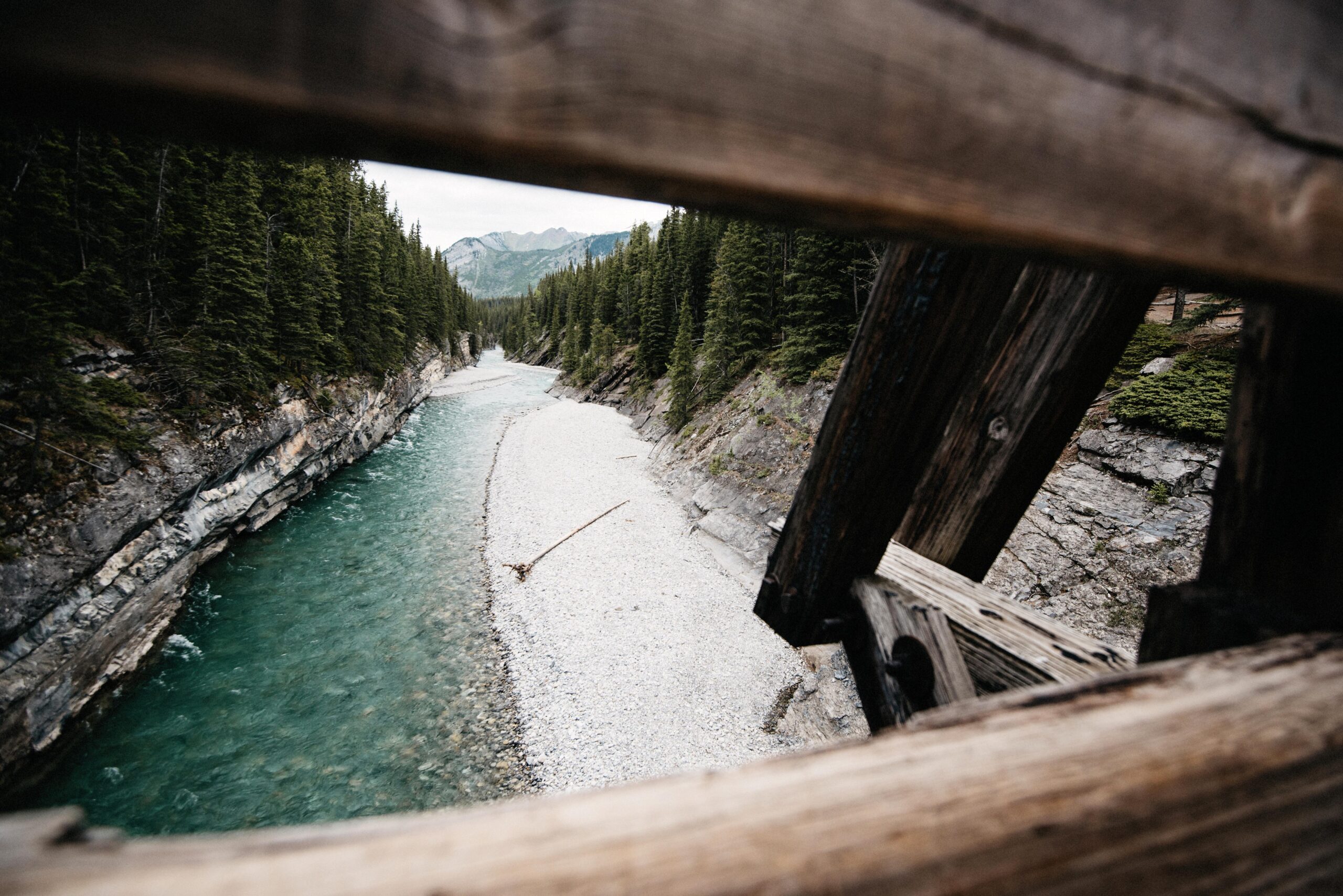 A wooden bridge above a clear mountain river gorge