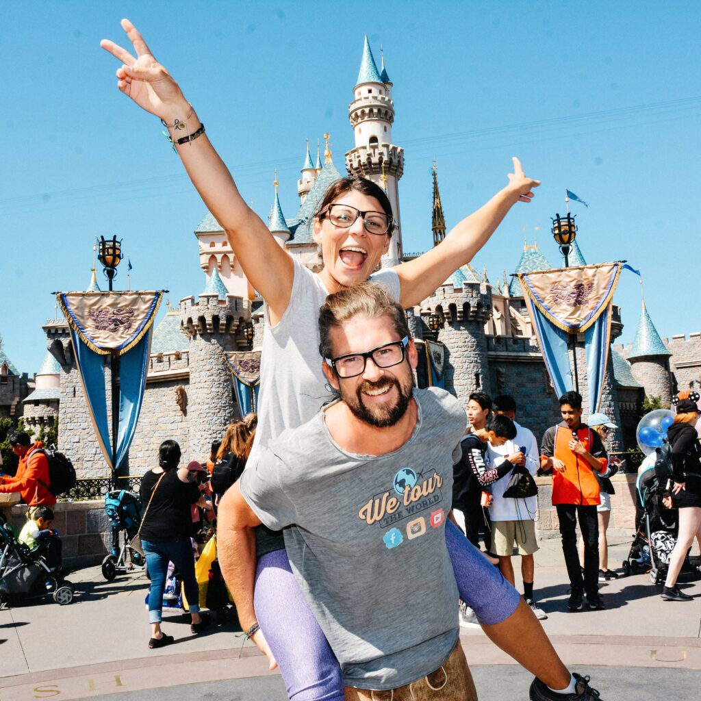 Bianca sitting on Tom's shoulders in front of Sleeping Beauty Castle at Disneyland
