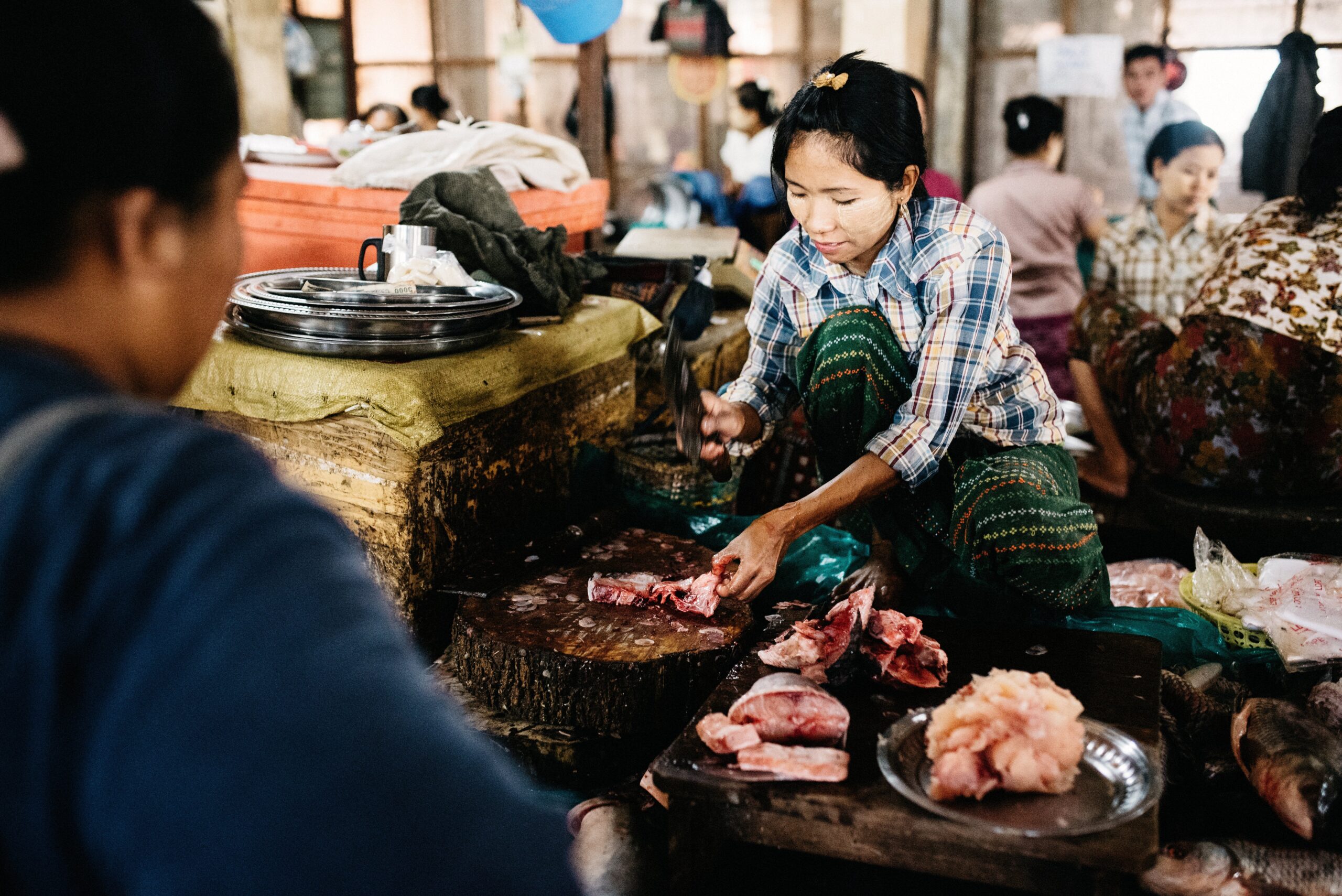 A vendor working at a busy meat stall in Mandalay