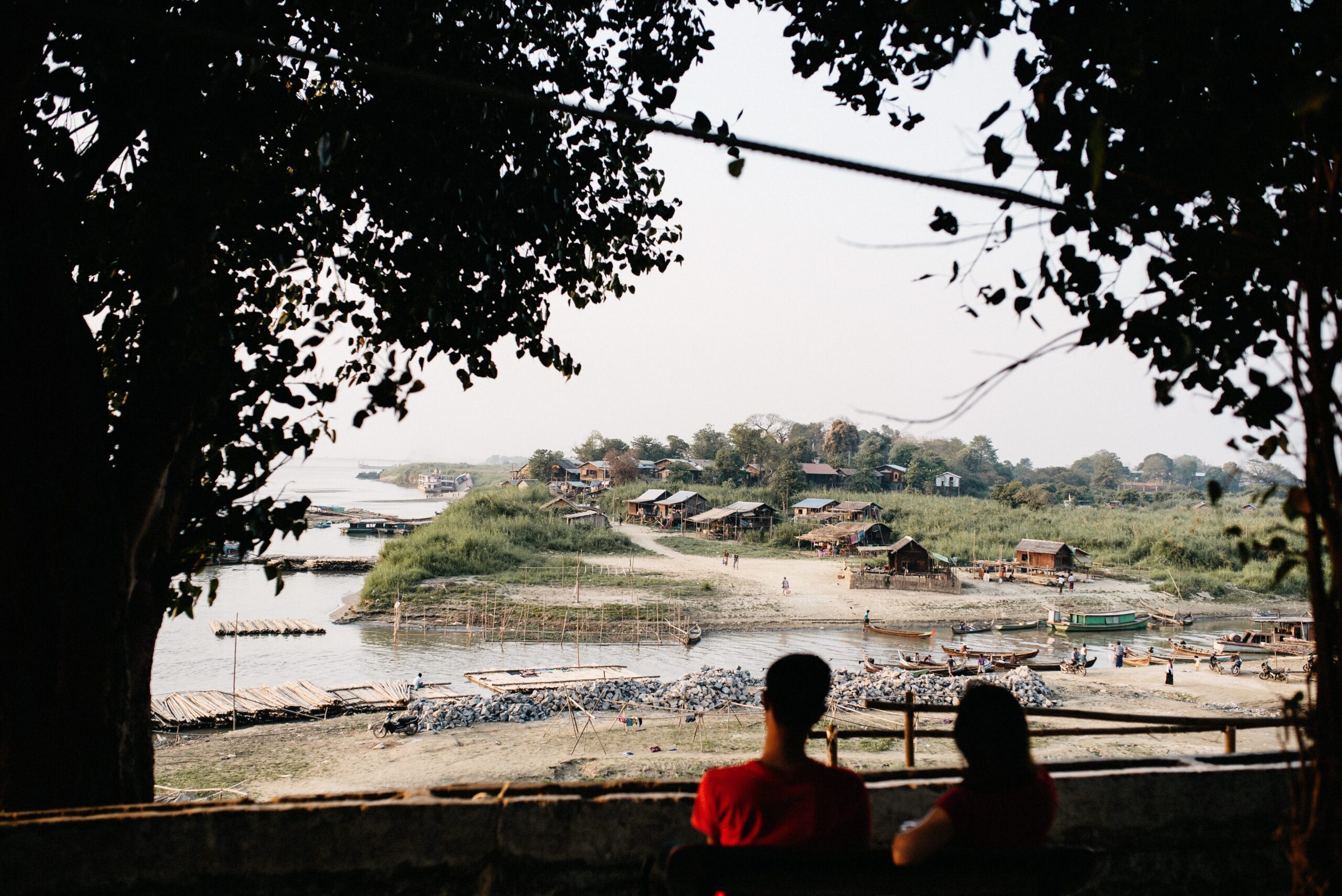 A person watching boats on the Irrawaddy River at sunset in Mandalay