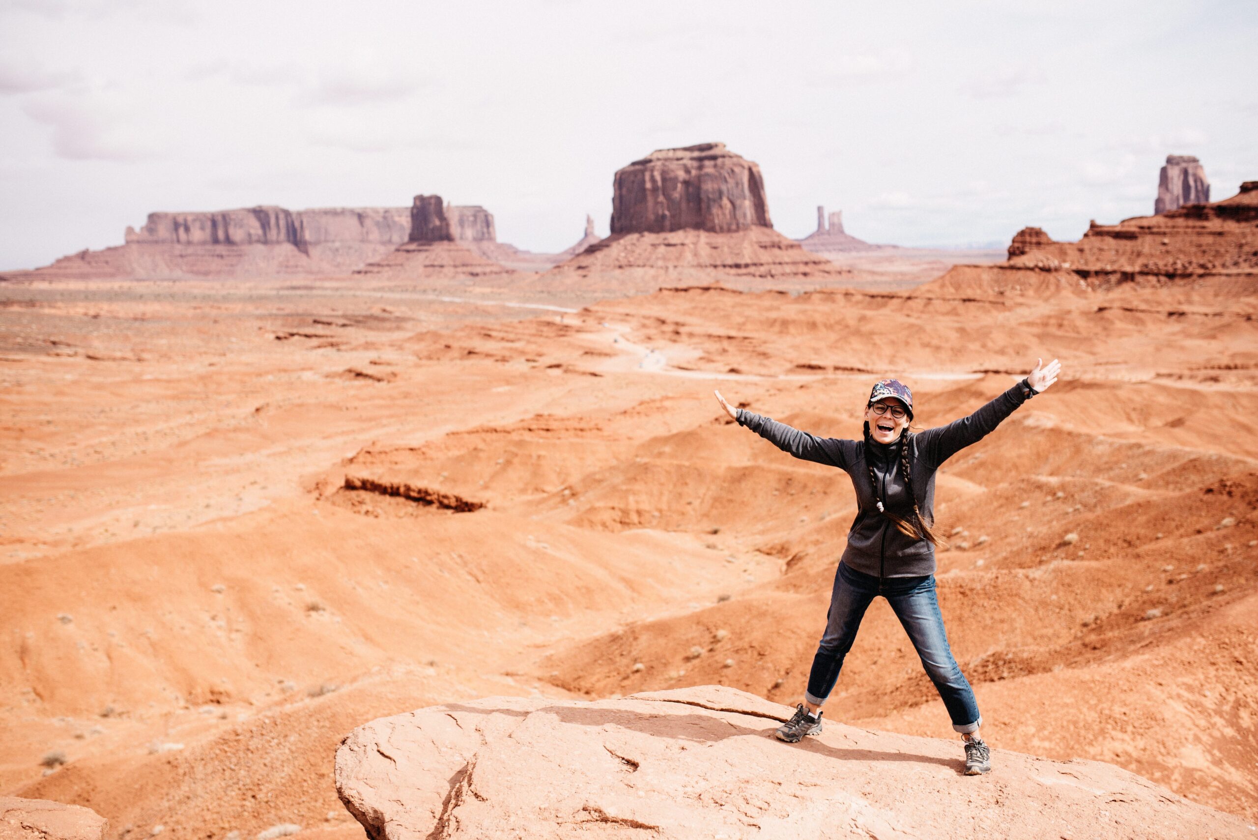Bianca standing with her arms open at a Monument Valley viewpoint