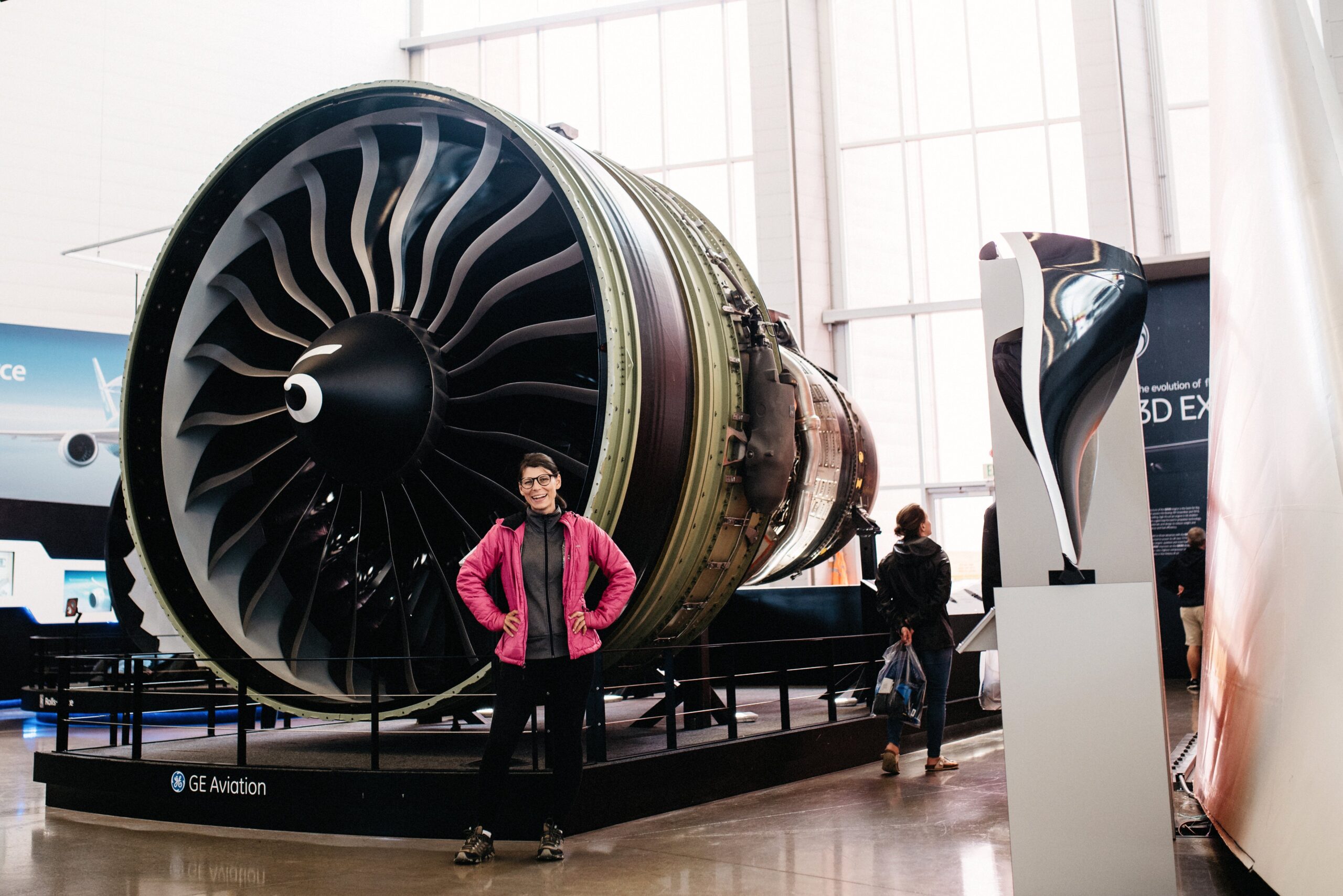 Bianca beside a large jet engine in the aviation exhibition