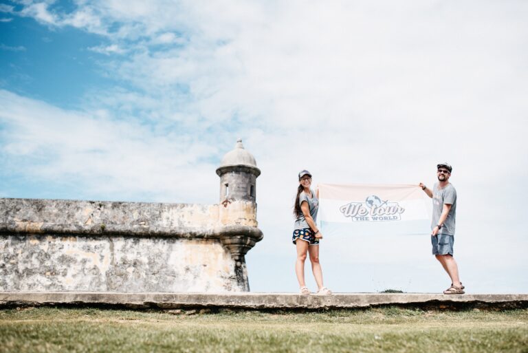 Bianca and Tom holding the We Tour The World flag at Castillo San Felipe del Morro in San Juan
