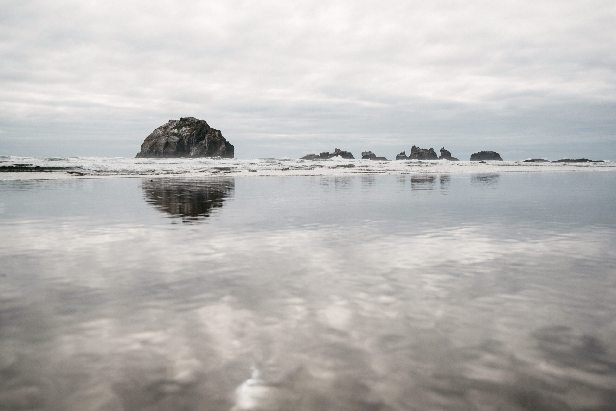 Felsformationen spiegeln sich an einem ruhigen Strand in Oregon