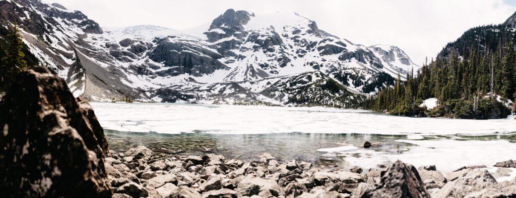 Upper Joffre Lake still covered in ice below the snowy mountains